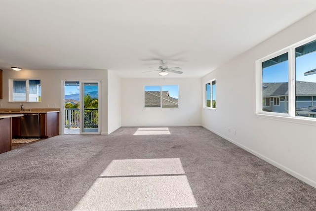 unfurnished living room with light carpet, sink, plenty of natural light, and ceiling fan