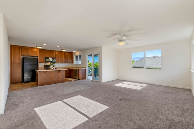 unfurnished living room with light colored carpet, ceiling fan, and sink