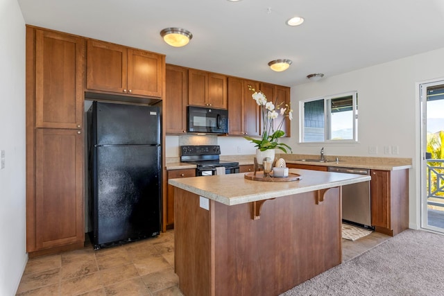 kitchen with a kitchen bar, a center island, black appliances, and sink