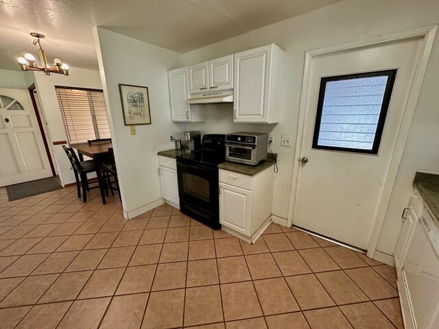 kitchen featuring electric range, light tile patterned floors, an inviting chandelier, white cabinets, and pendant lighting