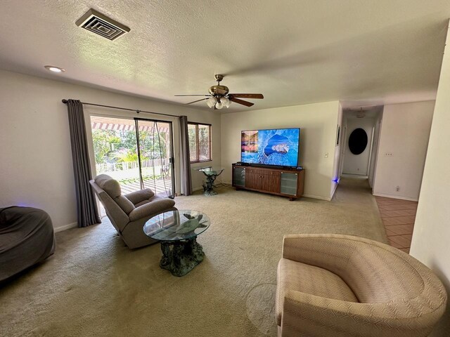 living room with a textured ceiling, carpet floors, and ceiling fan