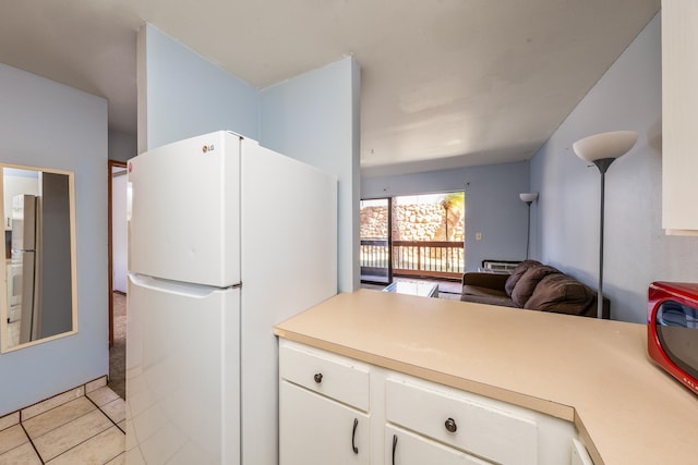 kitchen with stainless steel refrigerator, white cabinets, light tile patterned flooring, and white refrigerator