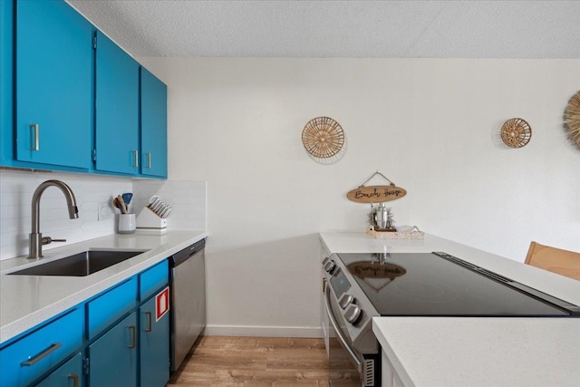 kitchen featuring electric range oven, a sink, stainless steel dishwasher, light wood-style flooring, and blue cabinetry