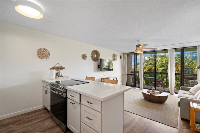 kitchen with electric stove, a textured ceiling, open floor plan, light countertops, and a wall of windows