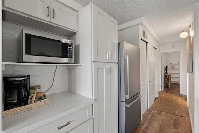 kitchen featuring appliances with stainless steel finishes, wood finished floors, light countertops, tasteful backsplash, and white cabinets