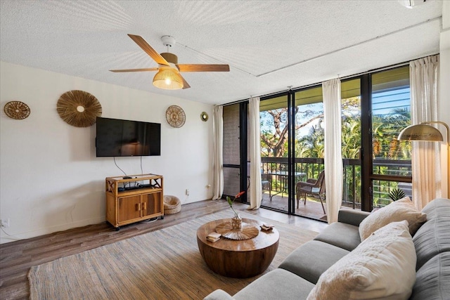 living room with floor to ceiling windows, a textured ceiling, ceiling fan, wood finished floors, and baseboards