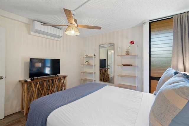 bedroom with a wall mounted AC, wood finished floors, a textured ceiling, and ceiling fan
