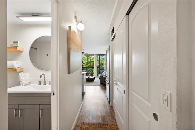 hallway with dark wood finished floors, a sink, and baseboards