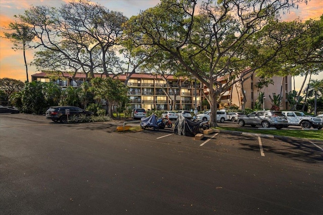 property at dusk with uncovered parking and a view of apartment building / complex