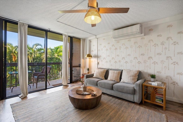 living room featuring a wall mounted AC, a wall of windows, wallpapered walls, a textured ceiling, and ceiling fan