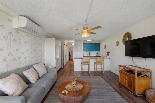 living area featuring a wall mounted AC, ceiling fan, dark wood-type flooring, a textured ceiling, and wallpapered walls