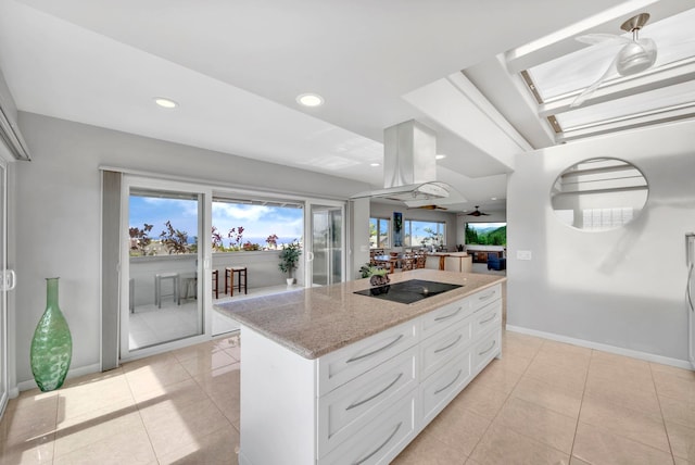 kitchen featuring light stone countertops, white cabinets, island range hood, light tile patterned floors, and black electric cooktop