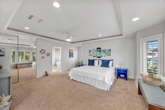 carpeted bedroom with ceiling fan, ensuite bathroom, and a tray ceiling