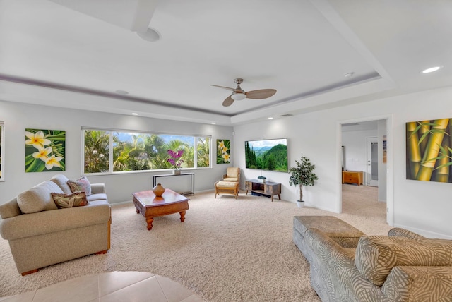 carpeted living room featuring ceiling fan and a raised ceiling