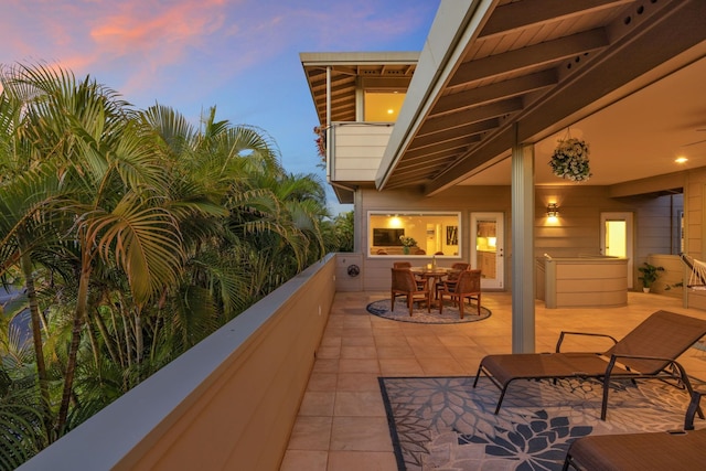 patio terrace at dusk featuring a balcony