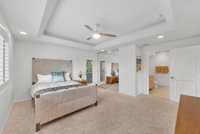 bedroom with ceiling fan, multiple windows, a tray ceiling, and light carpet