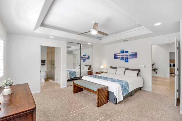 carpeted bedroom featuring connected bathroom, a tray ceiling, and ceiling fan