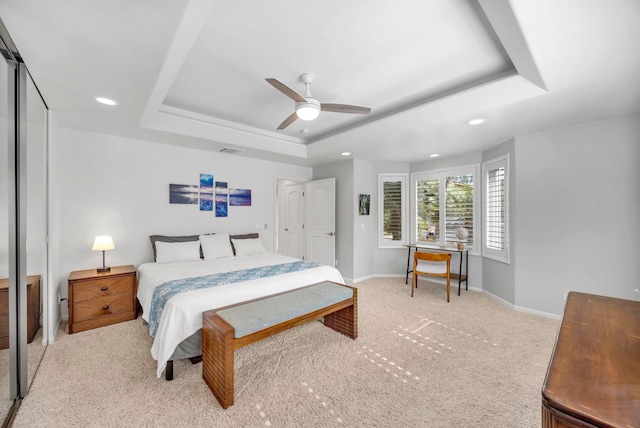 carpeted bedroom with ceiling fan and a tray ceiling