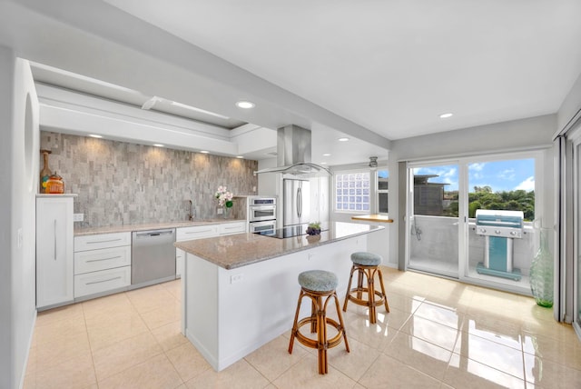 kitchen with appliances with stainless steel finishes, a kitchen island, island exhaust hood, sink, and a breakfast bar