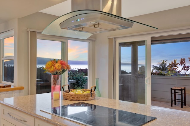 kitchen with black electric stovetop, white cabinets, and light stone countertops