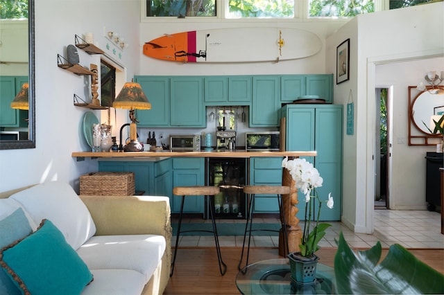 kitchen featuring refrigerator, blue cabinets, sink, wine cooler, and light tile patterned flooring