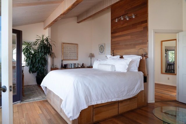 bedroom with lofted ceiling with beams, wood ceiling, wooden walls, and light hardwood / wood-style flooring