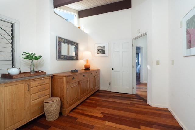 hall featuring beam ceiling, high vaulted ceiling, and dark wood-type flooring