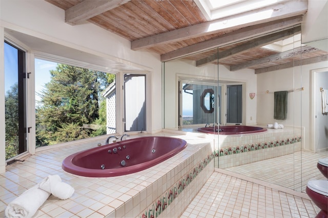 bathroom with a skylight, wooden ceiling, beamed ceiling, tile patterned flooring, and tiled bath