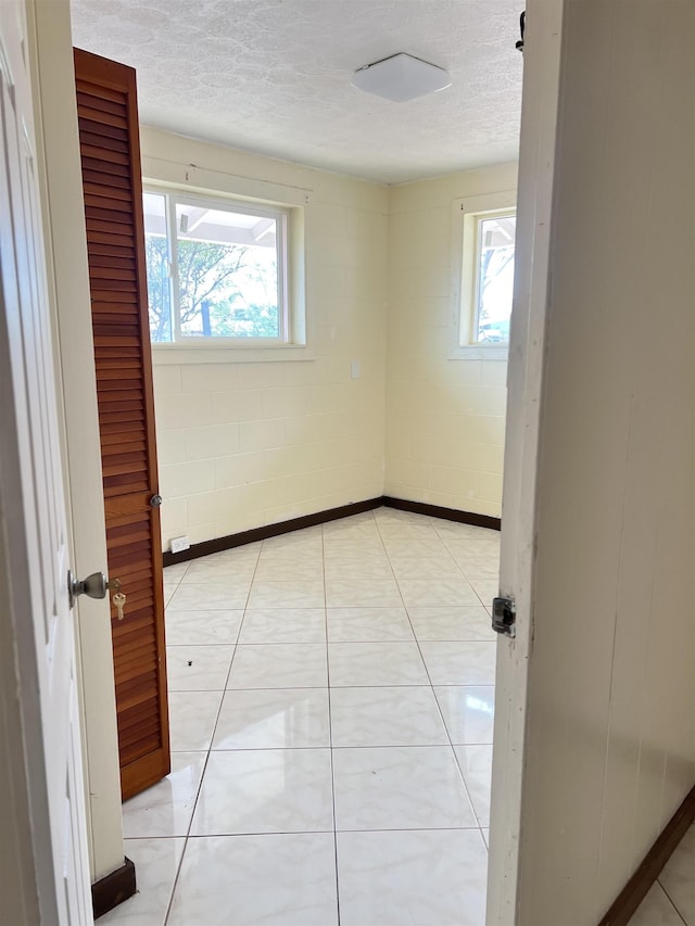 737 Kolani Pl, Wailuku, HI 96793 - unfurnished room with concrete block wall, a textured ceiling, light tile patterned flooring, and a wealth of natural light