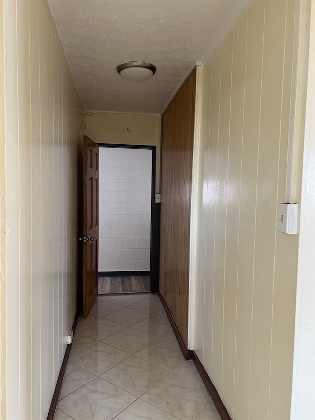 737 Kolani Pl, Wailuku, HI 96793 - hallway featuring a textured ceiling, wood walls, and light tile patterned floors