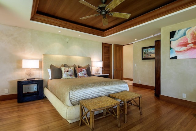 bedroom featuring a raised ceiling, ceiling fan, and hardwood / wood-style flooring