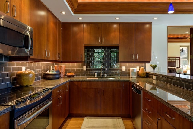 kitchen featuring decorative backsplash, sink, stainless steel appliances, and dark stone countertops