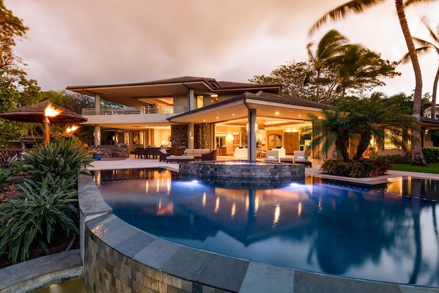 pool at dusk with outdoor lounge area, a jacuzzi, and a patio area