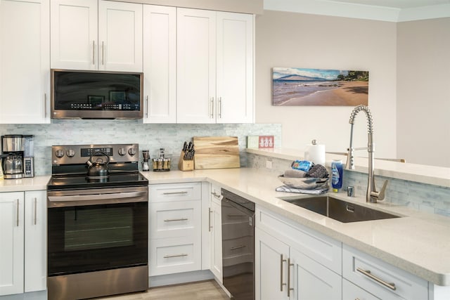 kitchen with white cabinets, stainless steel appliances, tasteful backsplash, sink, and light stone counters