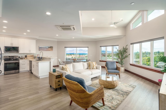 living room featuring ceiling fan, plenty of natural light, sink, and light hardwood / wood-style floors