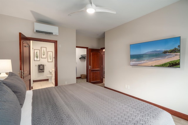 bedroom featuring an AC wall unit, ensuite bath, and ceiling fan