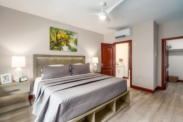 bedroom with ensuite bath, a closet, a wall unit AC, light wood-type flooring, and ceiling fan