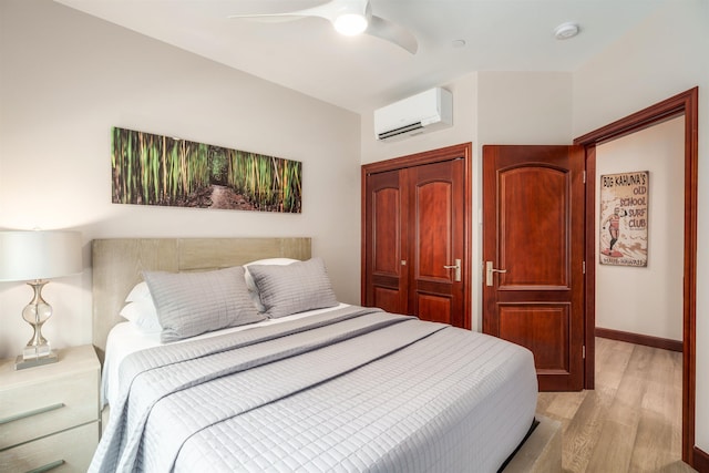 bedroom with ceiling fan, light hardwood / wood-style floors, and a wall unit AC