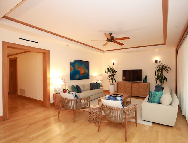 living room featuring ceiling fan, light hardwood / wood-style floors, and a tray ceiling