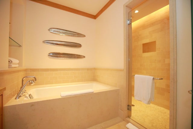 bathroom featuring tile walls, ornamental molding, and shower with separate bathtub