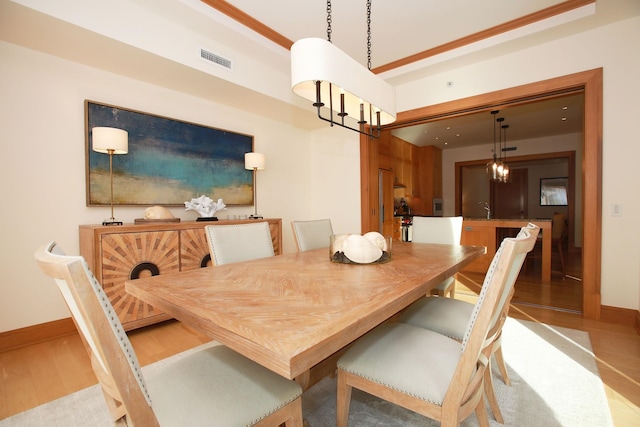 dining room with an inviting chandelier, sink, and light hardwood / wood-style flooring