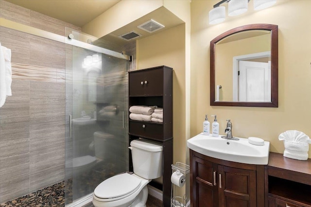 bathroom featuring a shower with door, vanity, and toilet