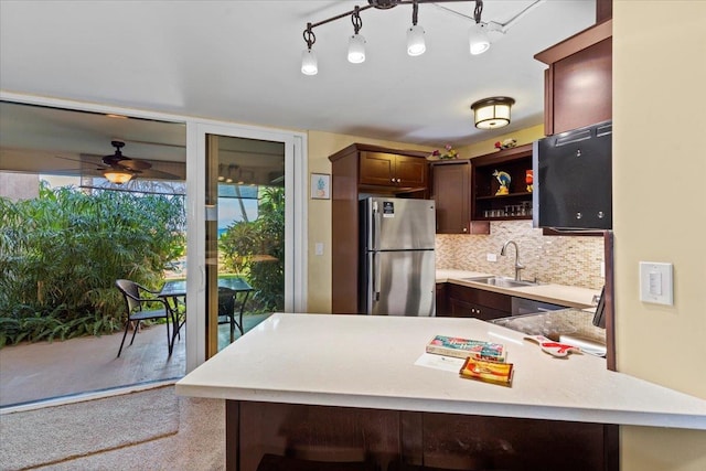 kitchen with stainless steel fridge, ceiling fan, sink, kitchen peninsula, and backsplash