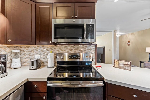 kitchen featuring appliances with stainless steel finishes, kitchen peninsula, dark brown cabinetry, and tasteful backsplash