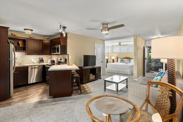 interior space with light wood-type flooring, tasteful backsplash, a kitchen island, stainless steel appliances, and a kitchen bar