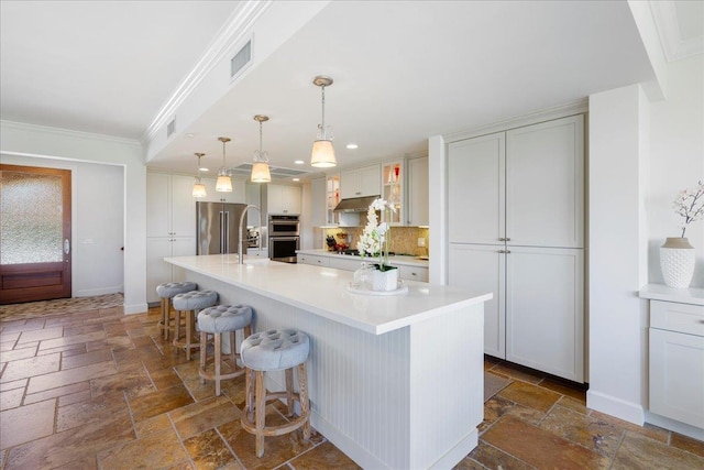 357 Umeke St Unit 144, Kihei, HI 96753 - kitchen with appliances with stainless steel finishes, light countertops, stone tile floors, a kitchen bar, and under cabinet range hood