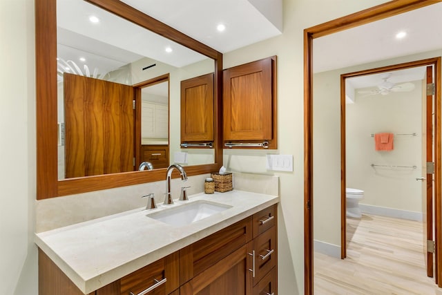 bathroom with hardwood / wood-style floors, vanity, toilet, and ceiling fan