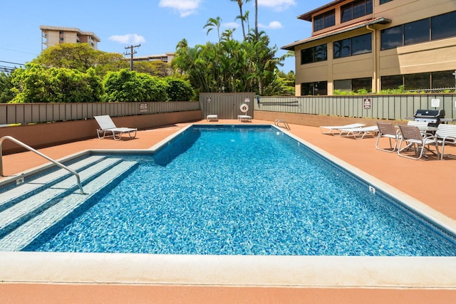 community pool featuring a patio area, area for grilling, and fence