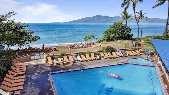 community pool with fence, a water and mountain view, and a gate