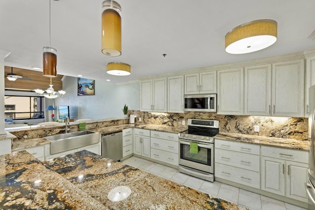 kitchen with hanging light fixtures, a sink, light tile patterned flooring, tasteful backsplash, and appliances with stainless steel finishes